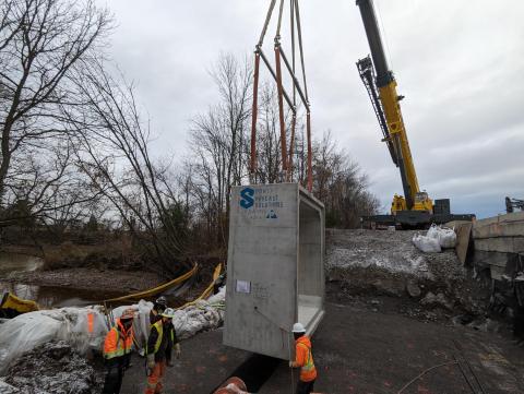 Crane lowering culvert to hole